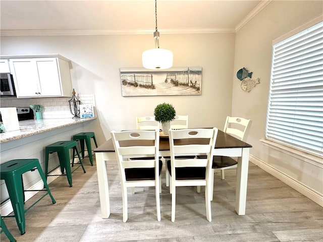 dining space featuring light wood-type flooring and ornamental molding