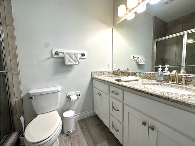 bathroom featuring hardwood / wood-style flooring, a shower with shower door, vanity, and toilet