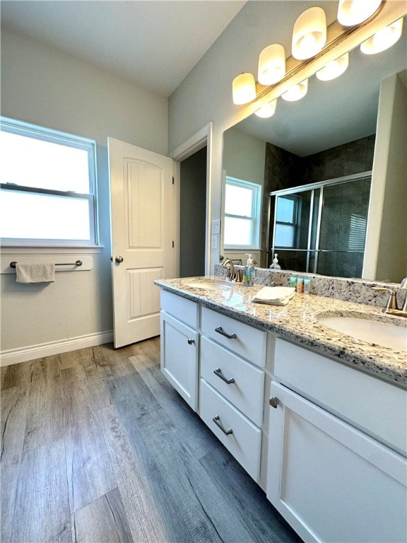 bathroom with wood-type flooring, vanity, and an enclosed shower