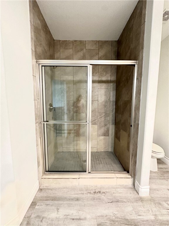 bathroom featuring a shower with shower door and toilet