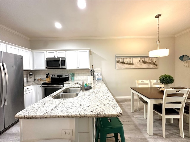 kitchen with white cabinets, decorative backsplash, light hardwood / wood-style flooring, pendant lighting, and appliances with stainless steel finishes