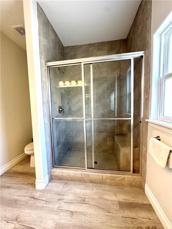 bathroom featuring toilet, hardwood / wood-style floors, and a shower with shower door