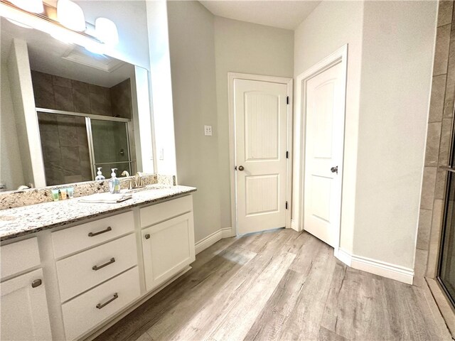 bathroom with walk in shower, wood-type flooring, and vanity