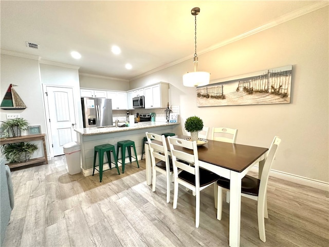 dining area with light hardwood / wood-style flooring and crown molding