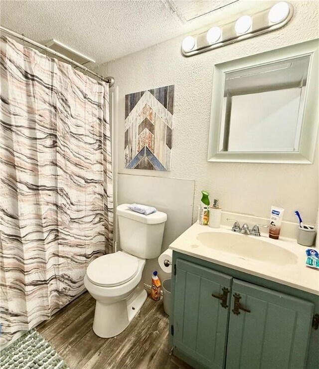 bathroom with hardwood / wood-style floors, a textured ceiling, toilet, vanity, and a shower with shower curtain