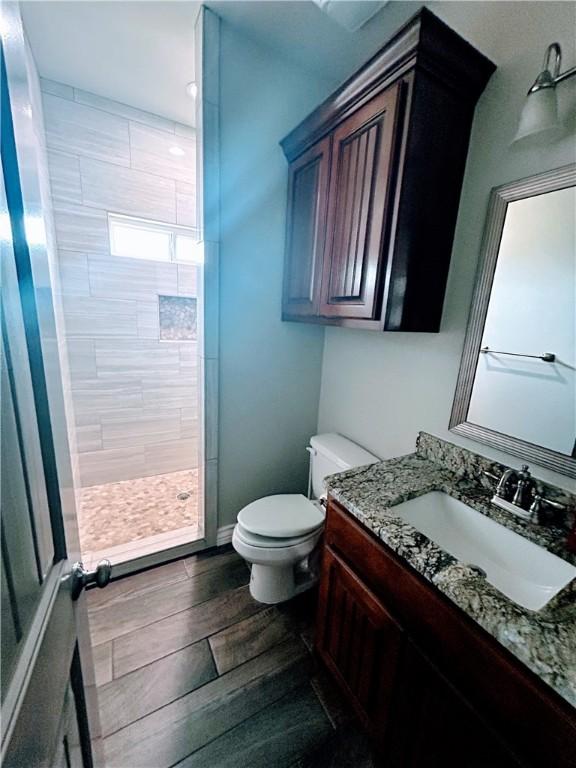 119 Moss, Odem, TX 78370 - bathroom featuring vanity, a stall shower, toilet, and wood finished floors