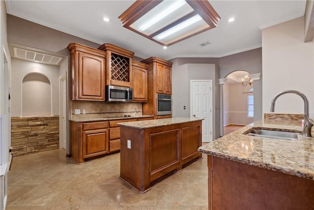 5609 Leicester Dr, Corpus Christi, TX 78414 - kitchen featuring appliances with stainless steel finishes, arched walkways, light stone counters, a kitchen island, and ornamental molding