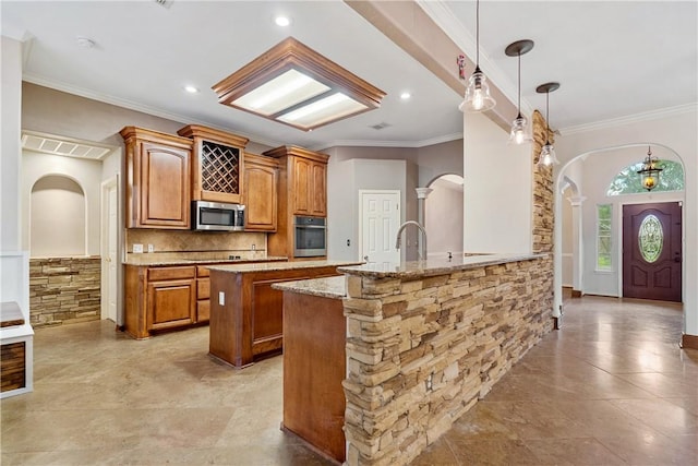 5609 Leicester Dr, Corpus Christi, TX 78414 - kitchen with stainless steel appliances, arched walkways, light stone countertops, brown cabinetry, and crown molding