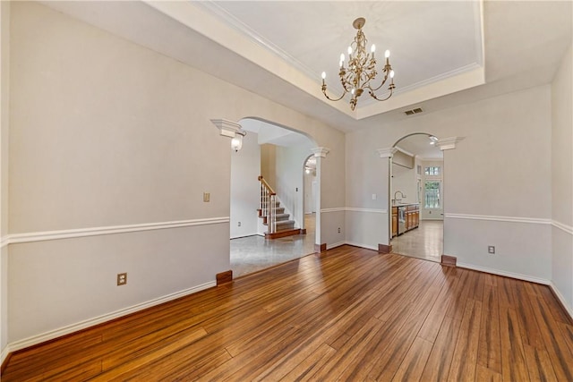 5609 Leicester Dr, Corpus Christi, TX 78414 - empty room with arched walkways, hardwood / wood-style flooring, a chandelier, a raised ceiling, and ornamental molding