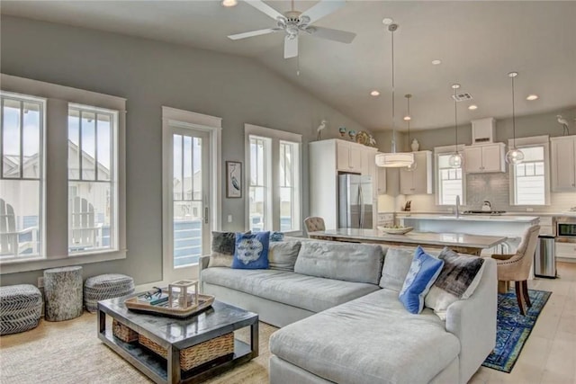 living room featuring ceiling fan, sink, vaulted ceiling, and light wood-type flooring