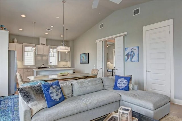 living room with vaulted ceiling, ceiling fan, and sink