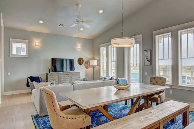 dining space featuring light wood-type flooring, lofted ceiling, ceiling fan, and a healthy amount of sunlight