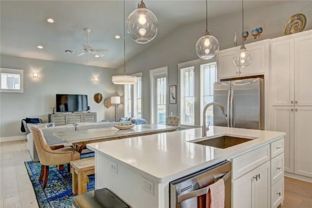 kitchen featuring lofted ceiling, a center island with sink, white cabinets, sink, and appliances with stainless steel finishes