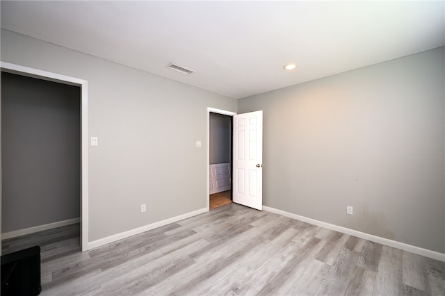 unfurnished bedroom with light wood-type flooring and a spacious closet