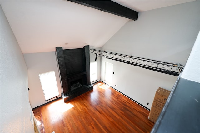 interior space with a brick fireplace, vaulted ceiling with beams, and light hardwood / wood-style flooring