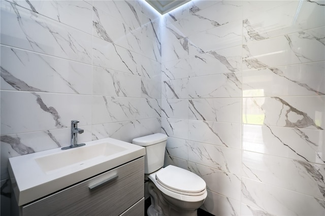 bathroom featuring tile walls, vanity, and toilet