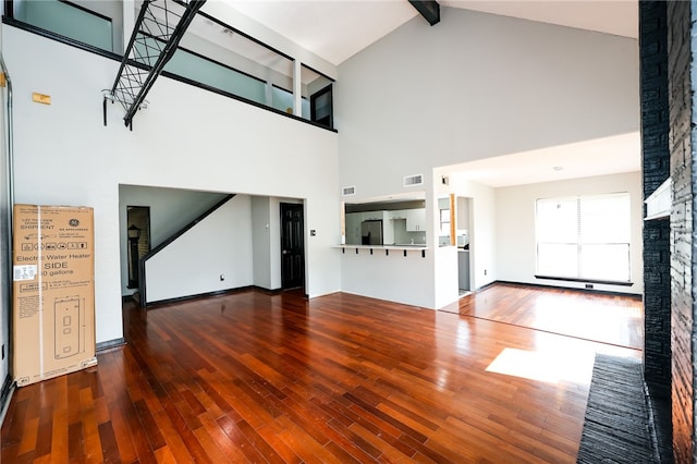 unfurnished living room with high vaulted ceiling, dark wood-type flooring, and beam ceiling