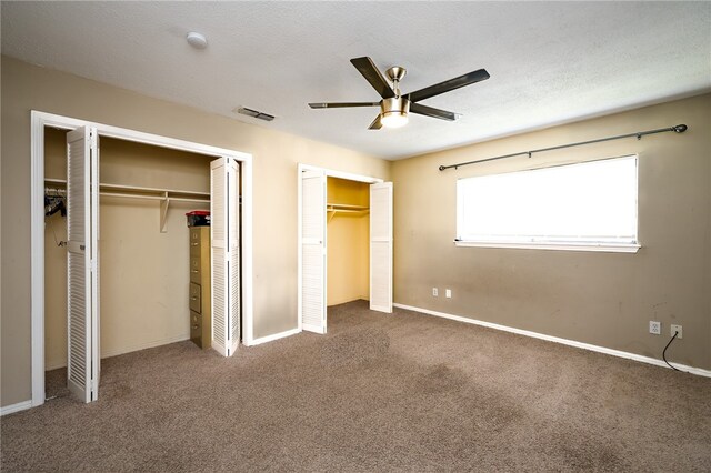 unfurnished bedroom with ceiling fan, carpet flooring, and multiple closets