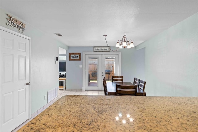 tiled dining area with a notable chandelier and french doors