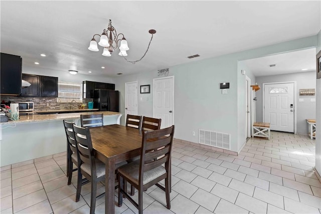 dining area featuring a notable chandelier, light tile patterned flooring, and sink