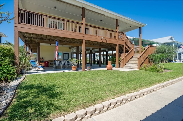 rear view of property featuring a lawn, a deck, stairs, and a patio
