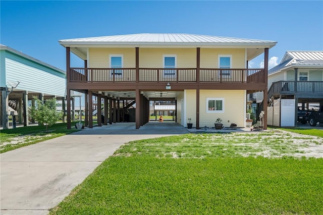 coastal inspired home with a front yard, a standing seam roof, a carport, and metal roof