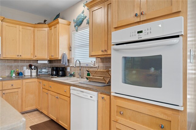 kitchen featuring light tile patterned flooring, sink, light brown cabinets, white appliances, and decorative backsplash