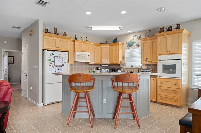 kitchen featuring white appliances, light brown cabinetry, decorative backsplash, and a wealth of natural light