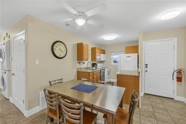 dining room featuring ceiling fan, light tile patterned floors, stacked washer and clothes dryer, and sink