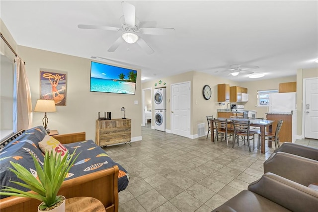 living room with ceiling fan, sink, and stacked washing maching and dryer