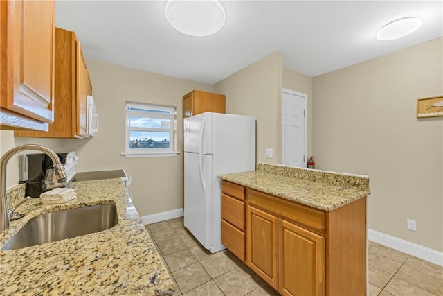 kitchen featuring light stone counters, sink, white appliances, and light tile patterned flooring