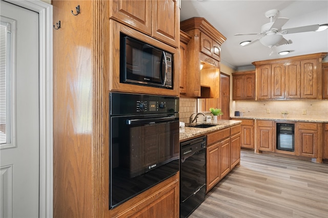 kitchen with beverage cooler, black appliances, sink, tasteful backsplash, and light hardwood / wood-style flooring