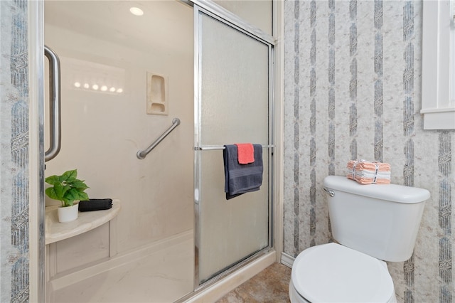 bathroom featuring a shower with shower door and toilet