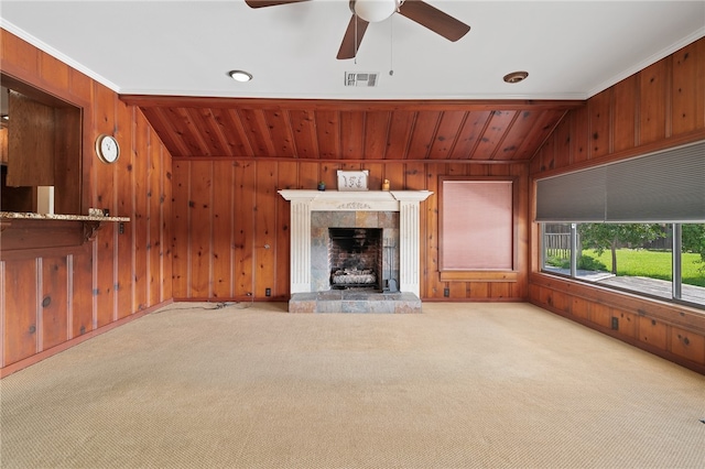 unfurnished living room featuring wooden walls, light colored carpet, crown molding, and a fireplace