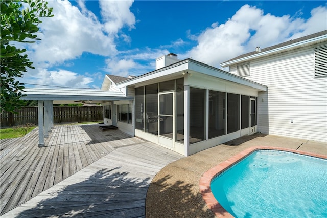 view of swimming pool featuring a sunroom and a wooden deck