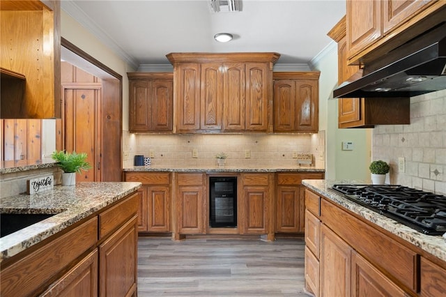 119 N Rife St, Aransas Pass, TX 78336 - kitchen with under cabinet range hood, wine cooler, black gas cooktop, ornamental molding, and decorative backsplash