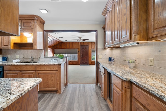 kitchen featuring light hardwood / wood-style floors, crown molding, backsplash, and light stone countertops