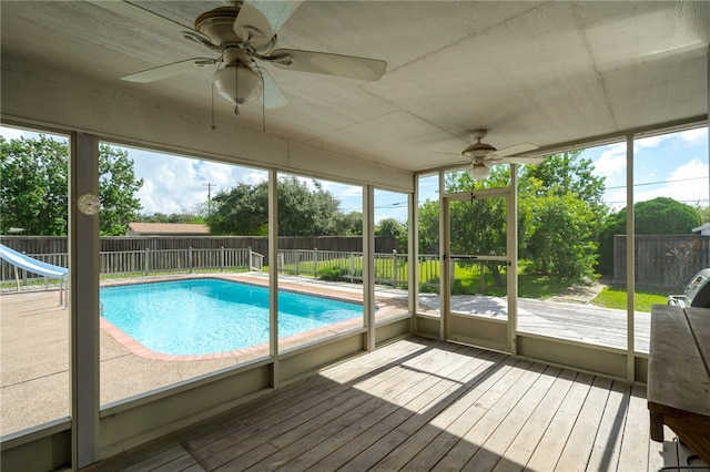 view of pool with a water slide, ceiling fan, and a deck