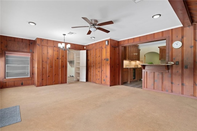 119 N Rife St, Aransas Pass, TX 78336 - unfurnished living room featuring wooden walls, a ceiling fan, light colored carpet, a chandelier, and crown molding