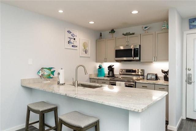 kitchen featuring a peninsula, appliances with stainless steel finishes, a sink, and recessed lighting