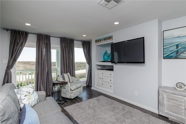 living area with dark wood-type flooring, recessed lighting, visible vents, and baseboards