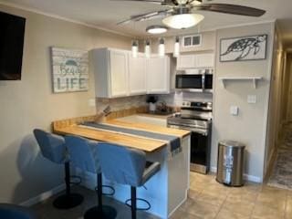 kitchen featuring a peninsula, appliances with stainless steel finishes, a breakfast bar area, and white cabinetry