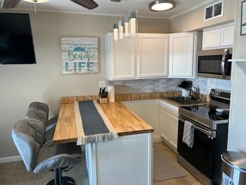 kitchen with pendant lighting, butcher block countertops, ceiling fan, appliances with stainless steel finishes, and white cabinetry