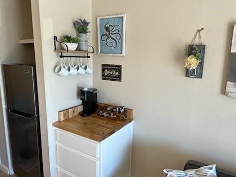 bar featuring stainless steel fridge and wooden counters