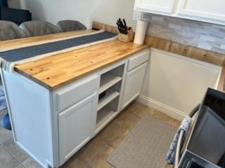 kitchen featuring open floor plan, butcher block counters, tile patterned flooring, and white cabinets