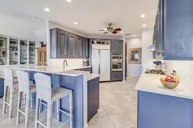 kitchen featuring kitchen peninsula, a kitchen bar, decorative backsplash, and appliances with stainless steel finishes