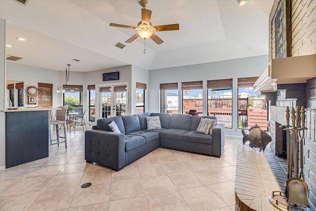 tiled living room with ceiling fan and a fireplace