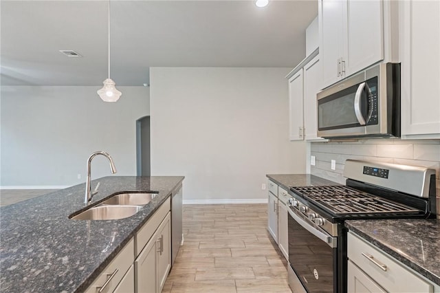 kitchen featuring pendant lighting, white cabinetry, sink, dark stone counters, and stainless steel appliances