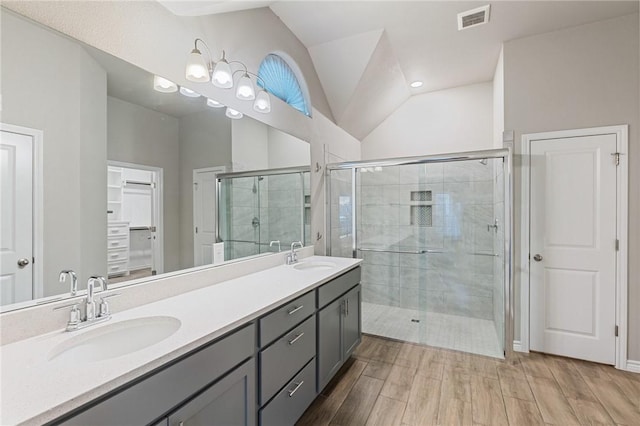 bathroom featuring wood-type flooring, vaulted ceiling, vanity, and walk in shower