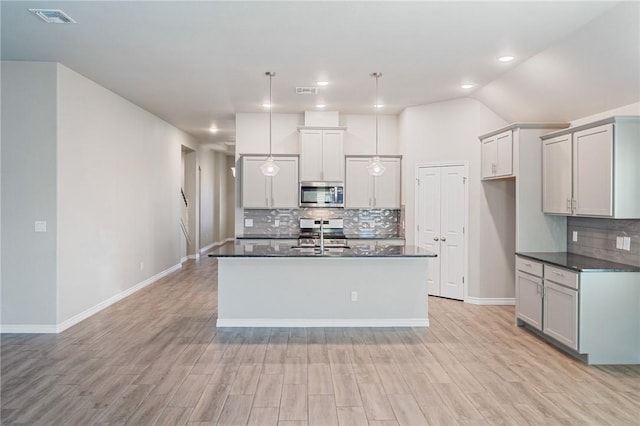 kitchen featuring gray cabinetry, an island with sink, pendant lighting, stainless steel appliances, and light hardwood / wood-style floors